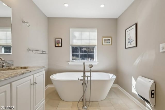 bathroom with tile patterned floors, recessed lighting, baseboards, a soaking tub, and vanity