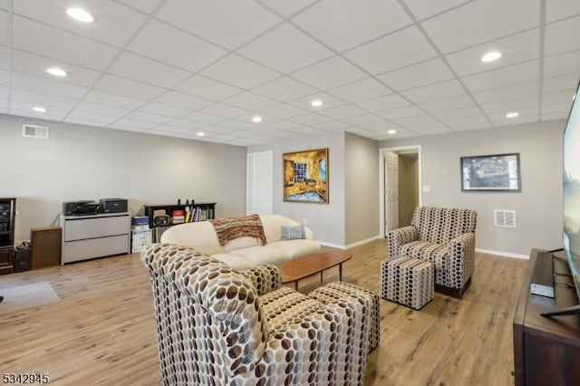 living area with a drop ceiling, visible vents, light wood-style floors, and recessed lighting