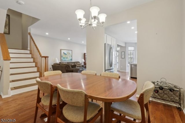 dining space featuring baseboards, a chandelier, stairs, recessed lighting, and wood finished floors