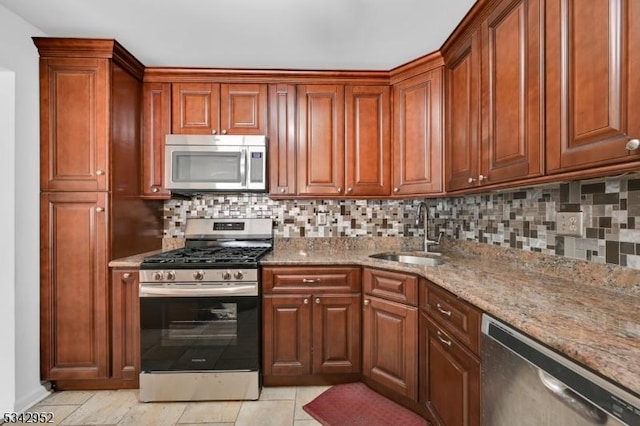 kitchen with a sink, backsplash, appliances with stainless steel finishes, light tile patterned floors, and light stone countertops