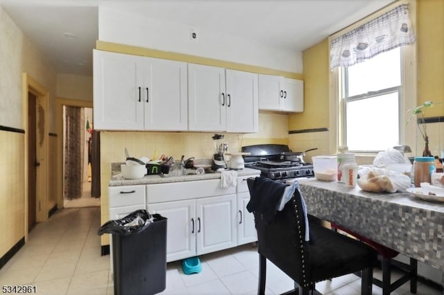 kitchen with light tile patterned floors, tasteful backsplash, light countertops, and white cabinetry