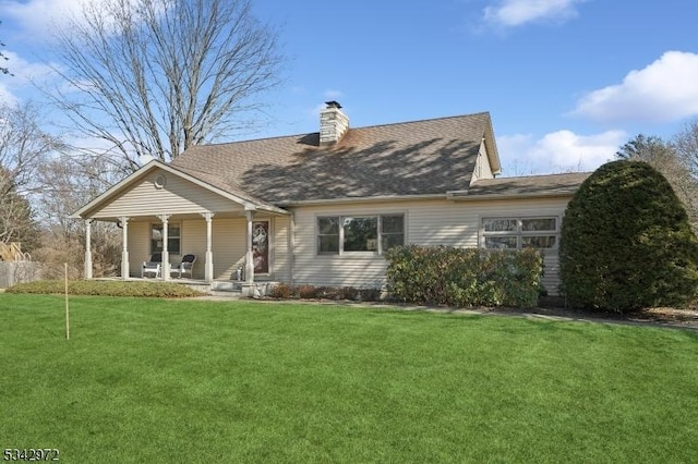 back of property with a porch, a chimney, a yard, and roof with shingles