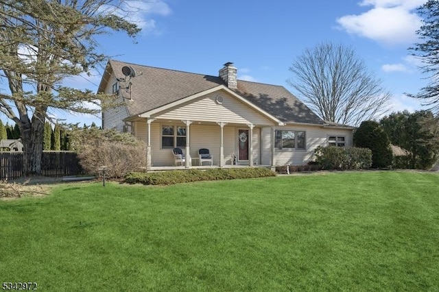 back of house with a porch, a chimney, a yard, and fence