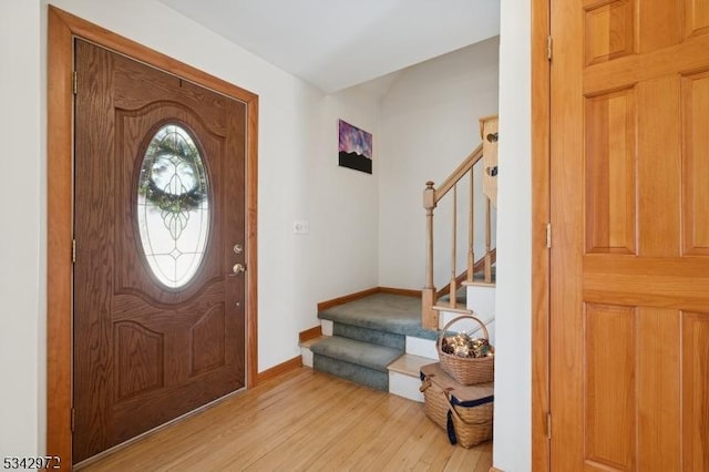 foyer entrance featuring stairs, baseboards, and wood finished floors