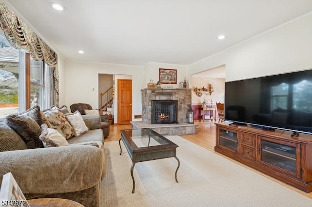 living room featuring recessed lighting, light wood-style floors, a stone fireplace, and ornamental molding