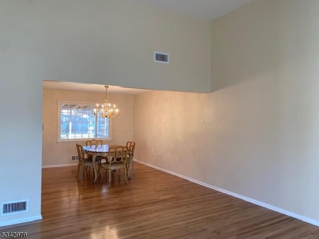 unfurnished dining area featuring a notable chandelier, wood finished floors, and visible vents