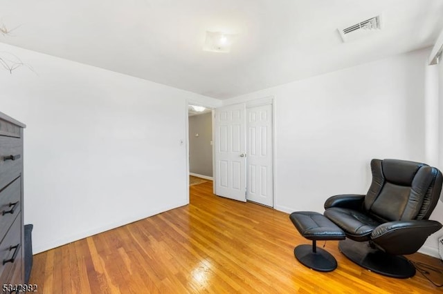 living area featuring baseboards, visible vents, and light wood-type flooring