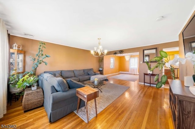 living room featuring a notable chandelier, baseboards, visible vents, and light wood finished floors