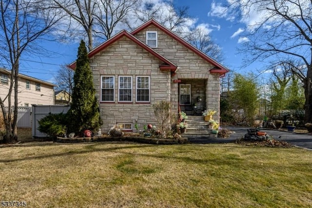 view of front of home with stone siding, a front lawn, and fence