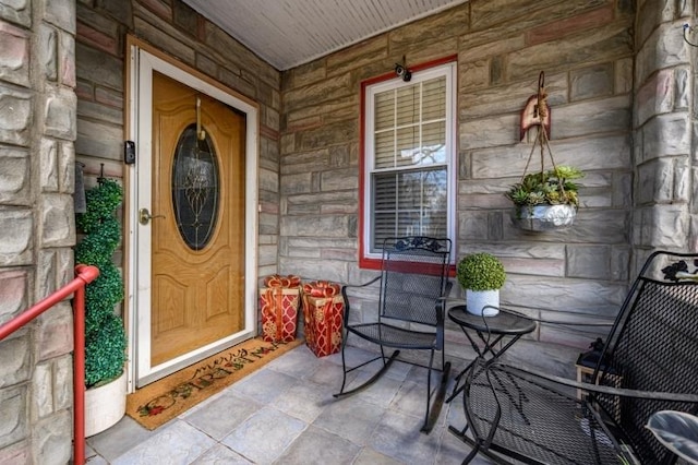 view of exterior entry with stone siding and a porch