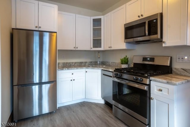 kitchen featuring a sink, white cabinets, light stone countertops, and stainless steel appliances