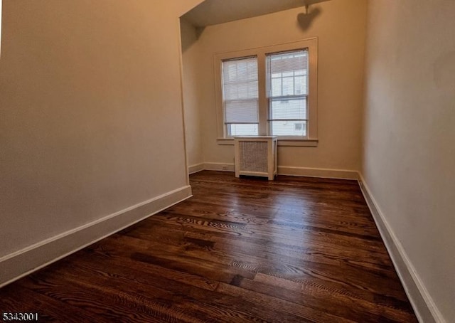 spare room with dark wood-style floors, radiator heating unit, and baseboards