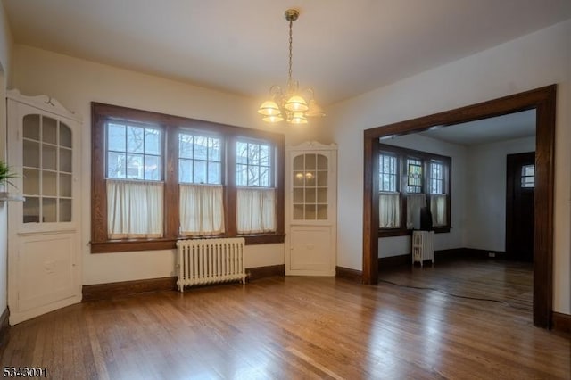 unfurnished dining area featuring baseboards, radiator, and wood finished floors