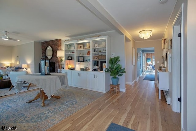 hallway with light wood-type flooring, baseboards, an inviting chandelier, and ornamental molding