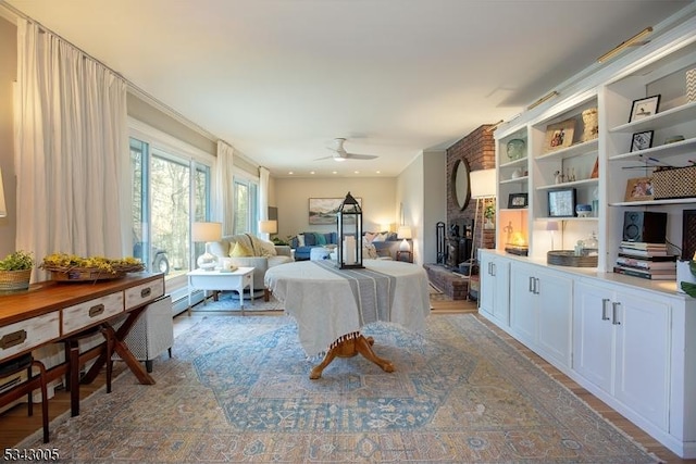 bedroom with a baseboard radiator, a brick fireplace, and wood finished floors