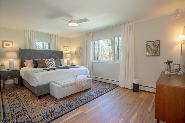 bedroom with baseboard heating, light wood-style flooring, and multiple windows