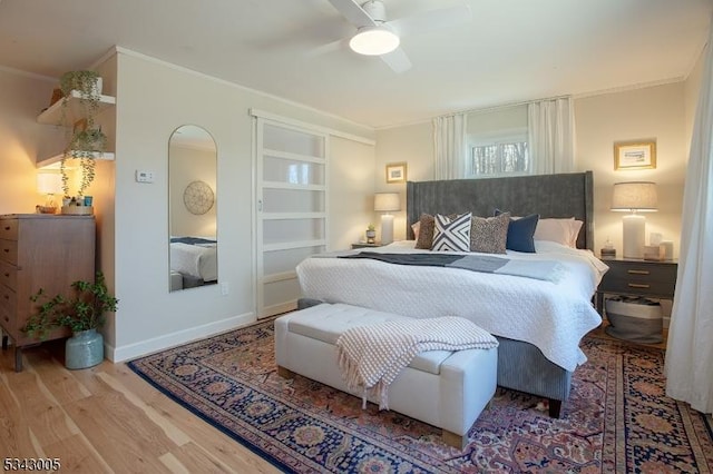 bedroom with ceiling fan, crown molding, baseboards, and wood finished floors