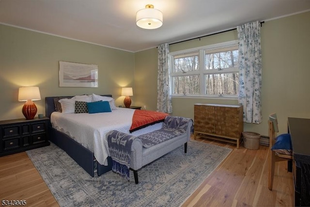 bedroom with ornamental molding and wood finished floors