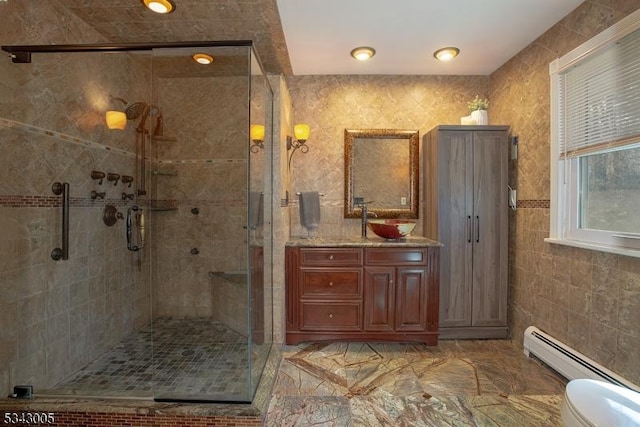 bathroom with toilet, tile walls, a shower stall, baseboard heating, and vanity