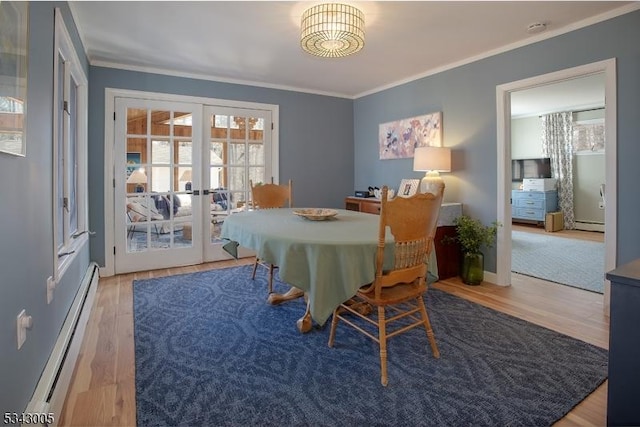 dining room featuring a baseboard heating unit, wood finished floors, ornamental molding, and french doors