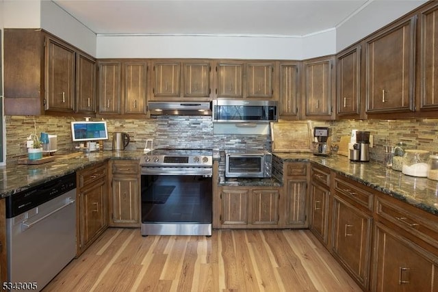 kitchen with light wood-style flooring, a toaster, under cabinet range hood, appliances with stainless steel finishes, and tasteful backsplash