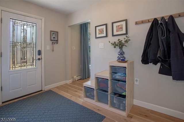 foyer with a baseboard heating unit, baseboards, and light wood finished floors