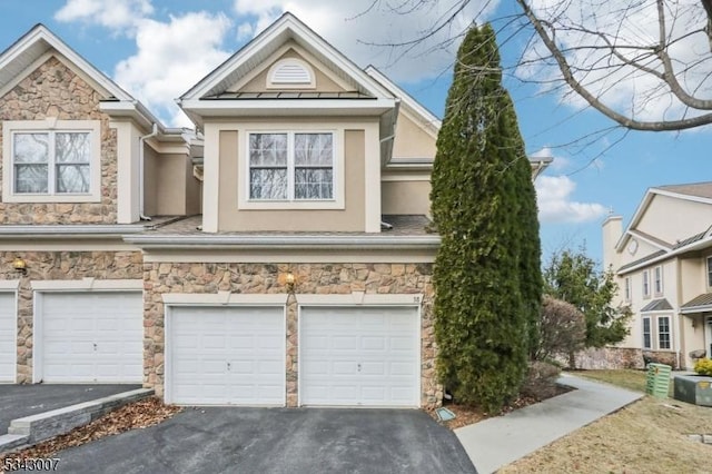 view of front of home with stucco siding, stone siding, and a garage