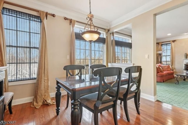 dining space with hardwood / wood-style flooring, baseboards, and ornamental molding