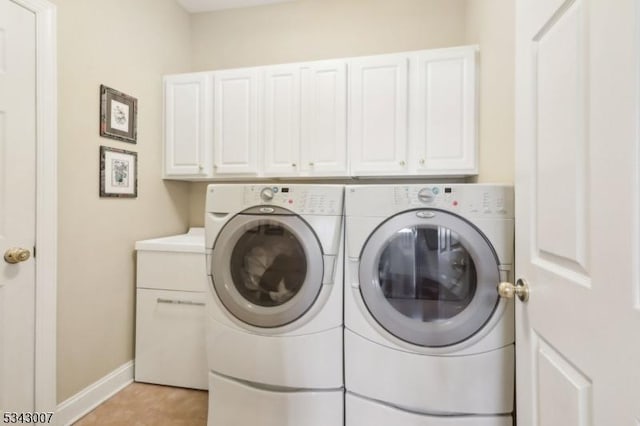 laundry room featuring cabinet space, baseboards, and washer and clothes dryer