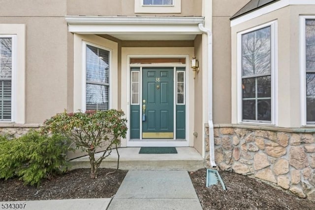 property entrance featuring stucco siding and stone siding