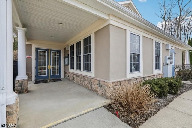 property entrance with french doors, stone siding, and stucco siding