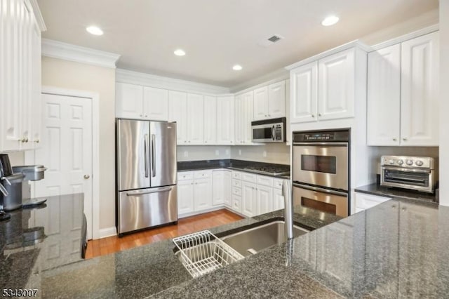 kitchen with wood finished floors, white cabinetry, recessed lighting, stainless steel appliances, and crown molding