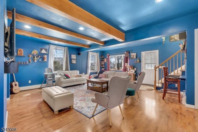 living room featuring a wealth of natural light, stairway, beam ceiling, and wood finished floors