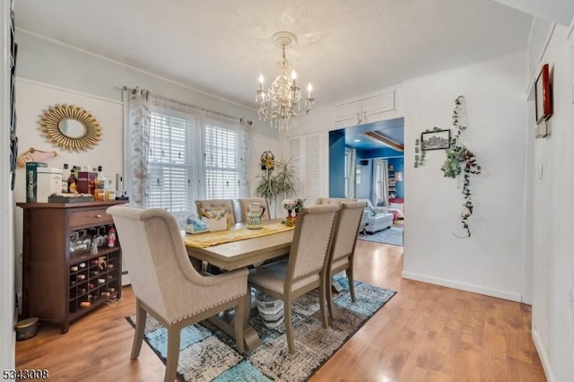 dining space featuring light wood-style flooring, a notable chandelier, and baseboards