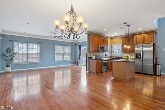 kitchen with dark countertops, open floor plan, a center island, stainless steel appliances, and crown molding