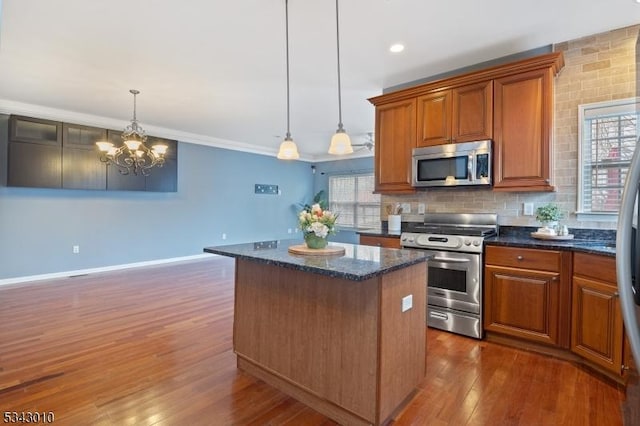 kitchen featuring backsplash, a center island, brown cabinetry, stainless steel appliances, and dark wood-style flooring