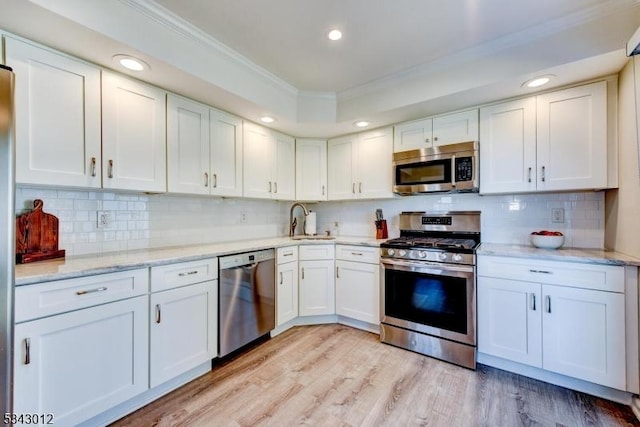 kitchen with a sink, ornamental molding, white cabinetry, and stainless steel appliances