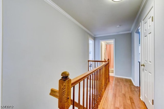 corridor with baseboards, an upstairs landing, ornamental molding, and light wood finished floors