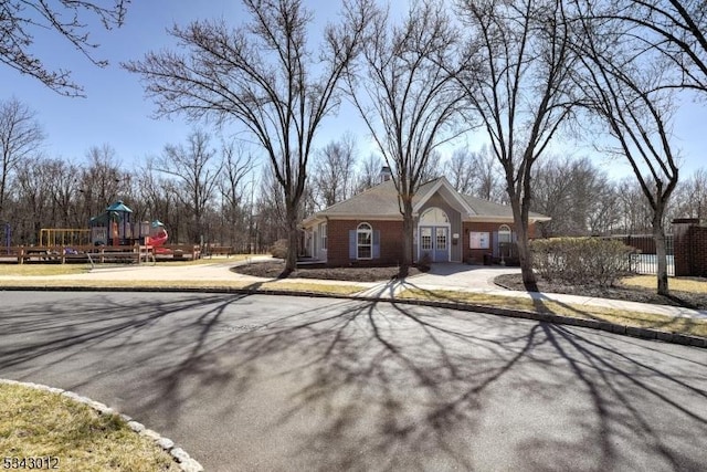 view of front of house featuring fence, brick siding, and playground community