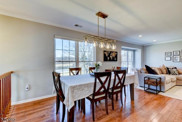 dining area featuring visible vents, baseboards, crown molding, and light wood-style floors