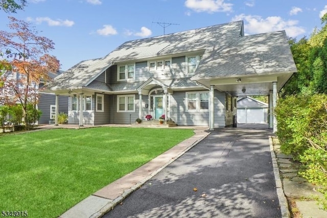 view of front of house featuring a front yard, an outbuilding, a carport, and aphalt driveway