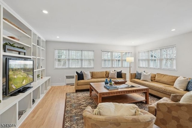 living room featuring recessed lighting, baseboards, light wood-style floors, and radiator heating unit