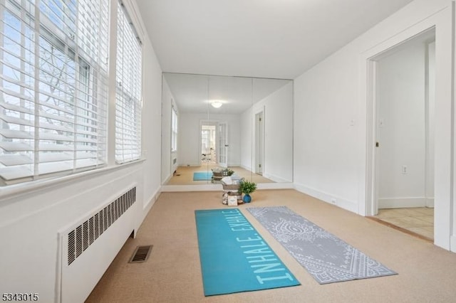 exercise area featuring visible vents, baseboards, radiator heating unit, and carpet