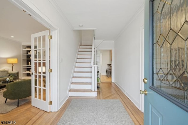 entrance foyer featuring stairway, crown molding, and wood finished floors