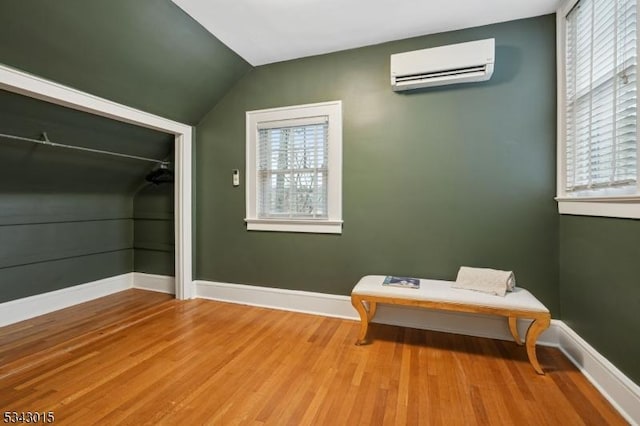 unfurnished room featuring an AC wall unit, plenty of natural light, wood finished floors, and baseboards