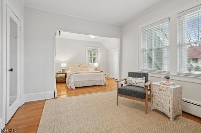 bedroom featuring baseboards, baseboard heating, light wood-style flooring, and ornamental molding