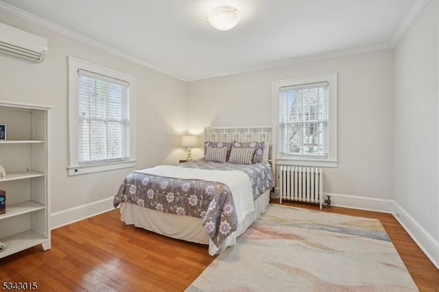 bedroom with multiple windows, radiator, a wall unit AC, and wood finished floors