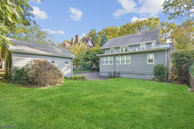 rear view of property featuring central AC unit, a lawn, a chimney, and fence