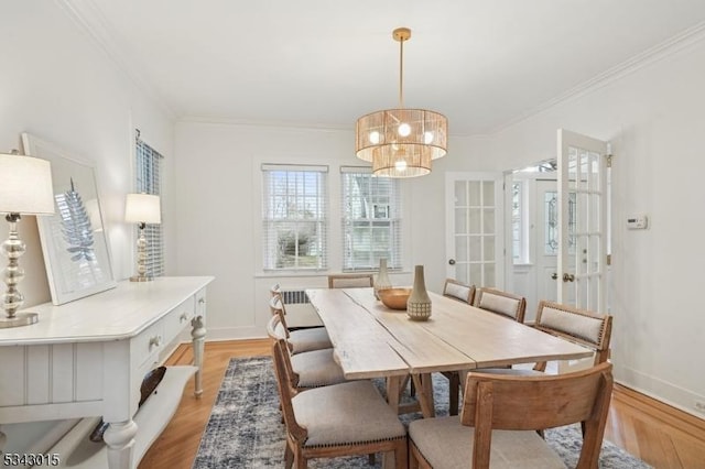 dining area with crown molding, a notable chandelier, baseboards, and light wood finished floors