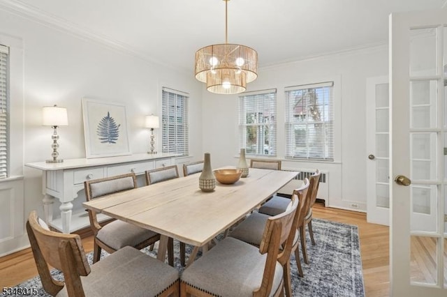 dining room featuring crown molding, a chandelier, radiator heating unit, light wood-type flooring, and french doors